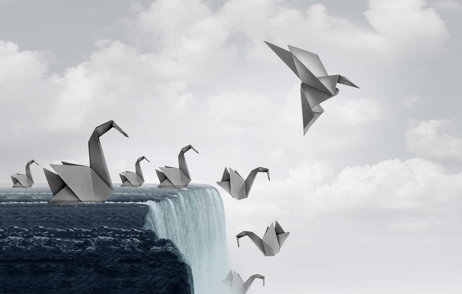 Origami swans at the edge of a waterfall. All but one swan is falling down. One swan has changed shape and flies off into the air.